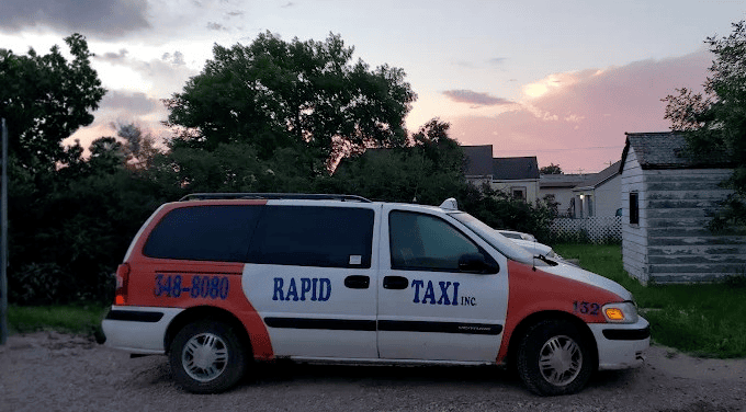A white and orange minivan with 605-348-8080 and Rapid Taxi Inc. text in blue text.